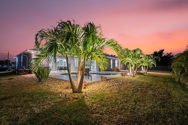yard at dusk with fence, an outdoor pool, and a patio area