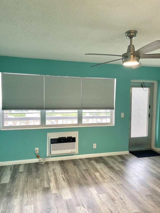 unfurnished living room featuring baseboards, a ceiling fan, a textured ceiling, and wood finished floors