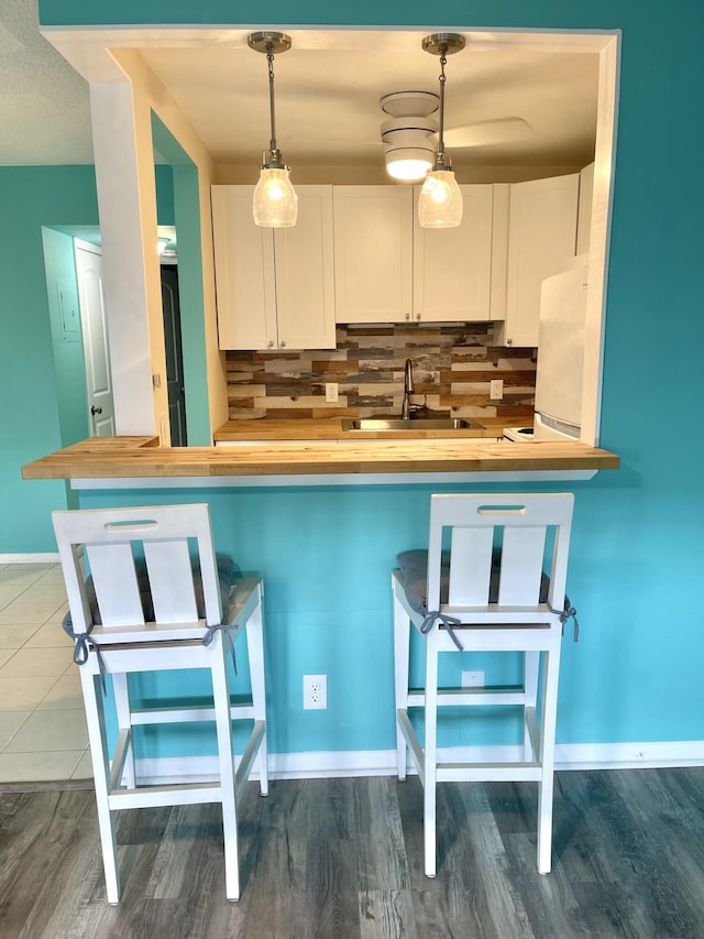 kitchen featuring butcher block countertops, freestanding refrigerator, decorative backsplash, and white cabinets