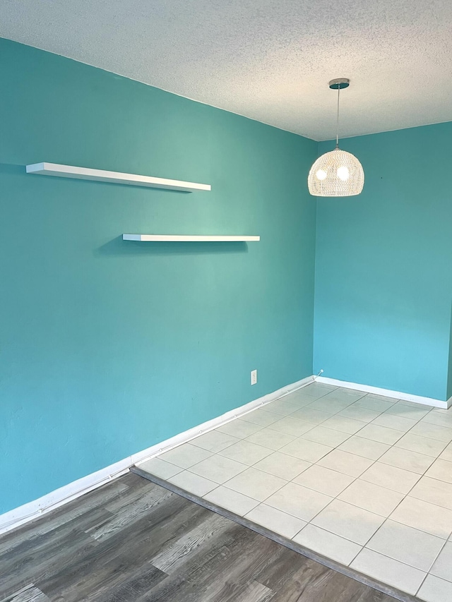 empty room featuring baseboards, a textured ceiling, and wood finished floors