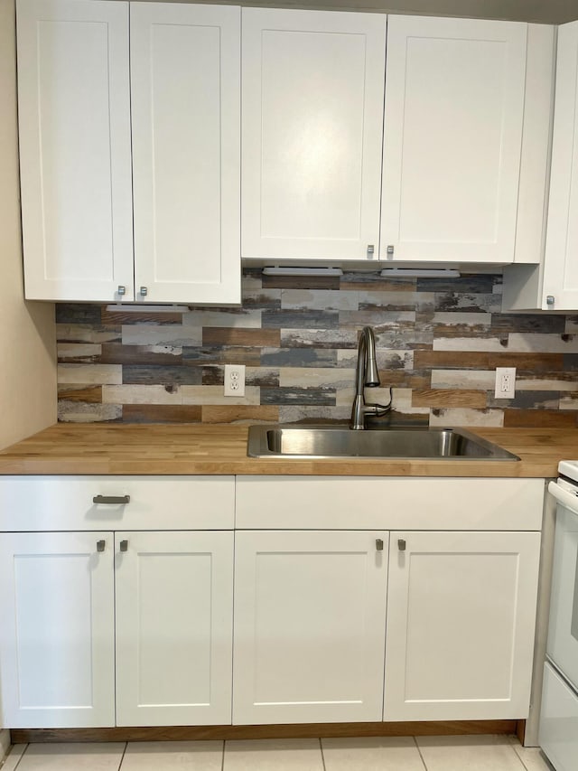 kitchen featuring a sink, wood counters, and white cabinets