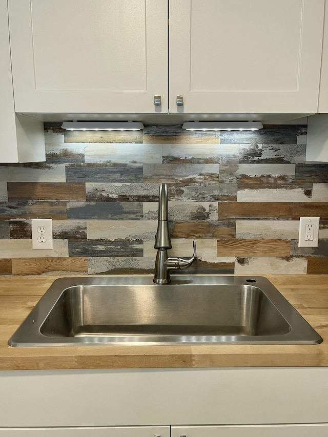 room details with white cabinets, a sink, and tasteful backsplash