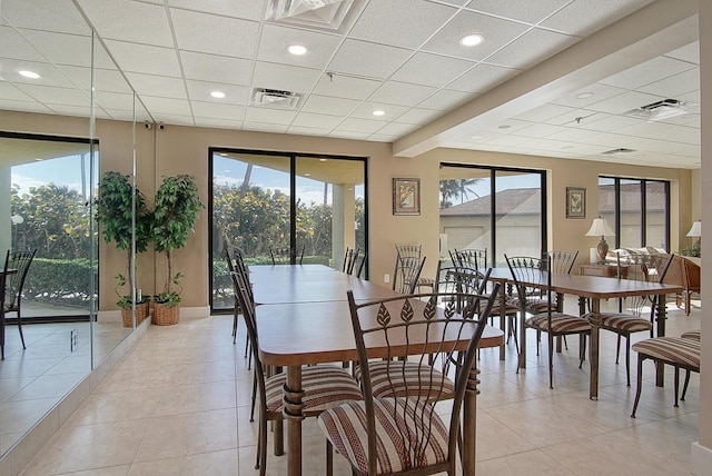 dining space featuring visible vents, a drop ceiling, light tile patterned floors, and a healthy amount of sunlight