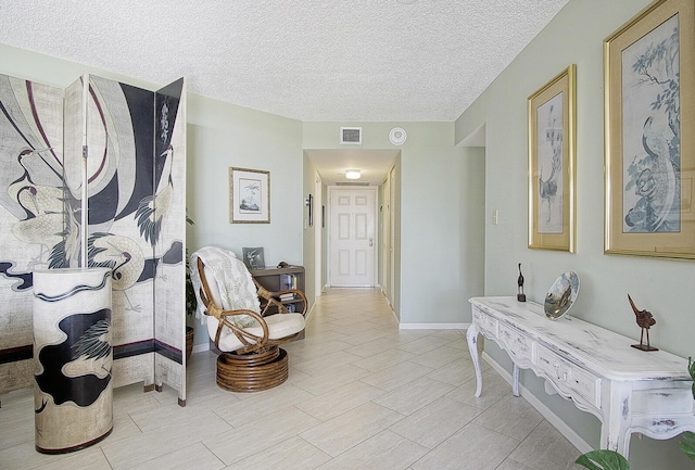 corridor featuring visible vents, a textured ceiling, and baseboards