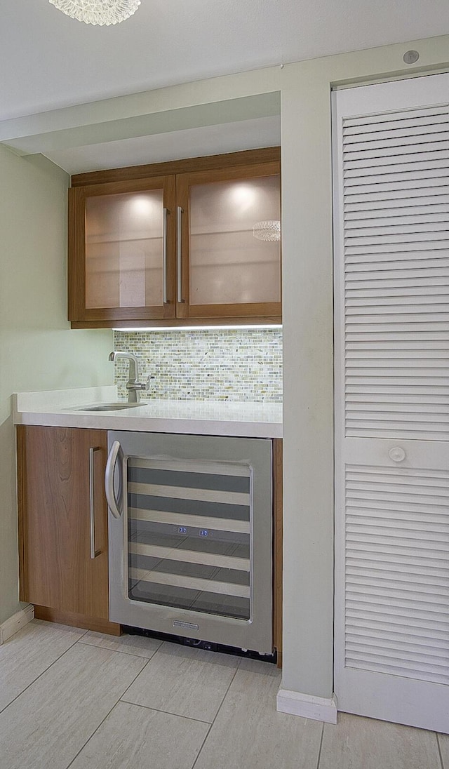 bar with beverage cooler, a sink, baseboards, and decorative backsplash