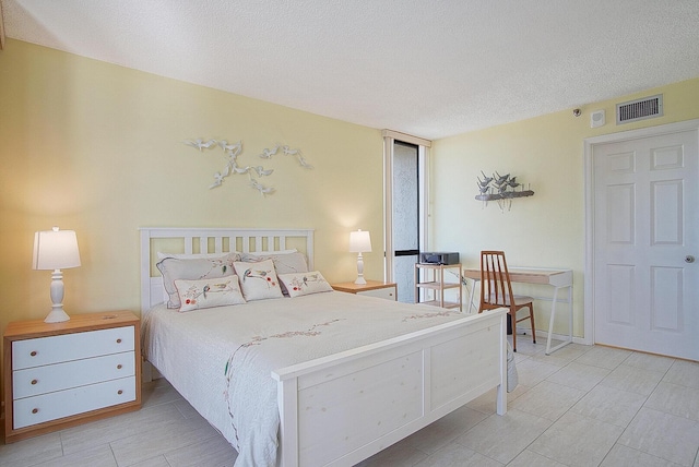 tiled bedroom with a textured ceiling and visible vents