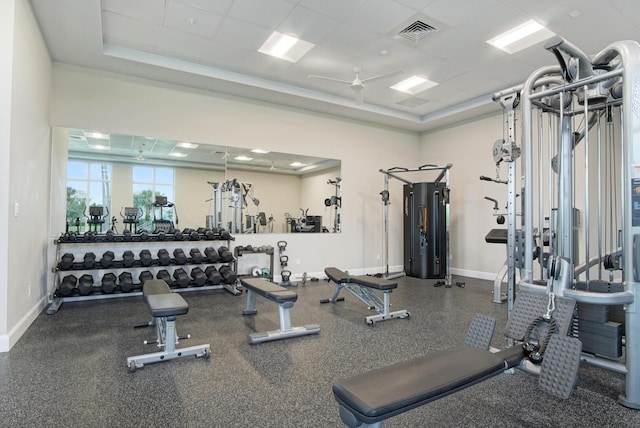 workout area featuring baseboards, a ceiling fan, a tray ceiling, and visible vents