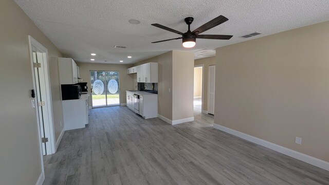unfurnished living room featuring a ceiling fan, baseboards, light wood finished floors, and a textured ceiling