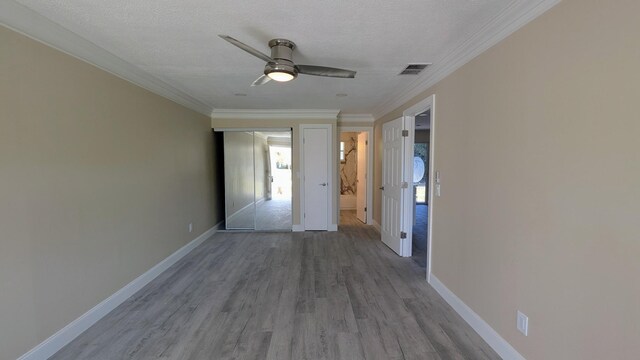 interior space featuring visible vents, crown molding, wood finished floors, baseboards, and a textured ceiling