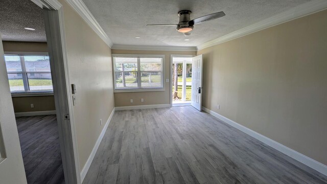 unfurnished room featuring ceiling fan, a textured ceiling, crown molding, wood finished floors, and baseboards