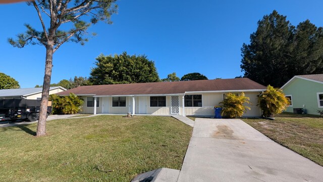 ranch-style home featuring central AC unit, a front lawn, covered porch, and concrete driveway