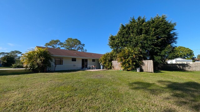 rear view of property featuring a lawn and fence