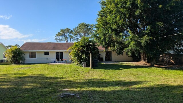 back of house with central AC unit, a patio area, and a yard