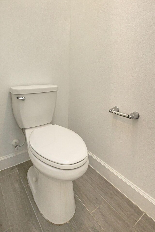 bathroom featuring baseboards, wood tiled floor, and toilet