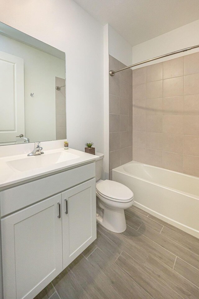 bathroom with vanity, toilet, wood finished floors, and shower / bathing tub combination