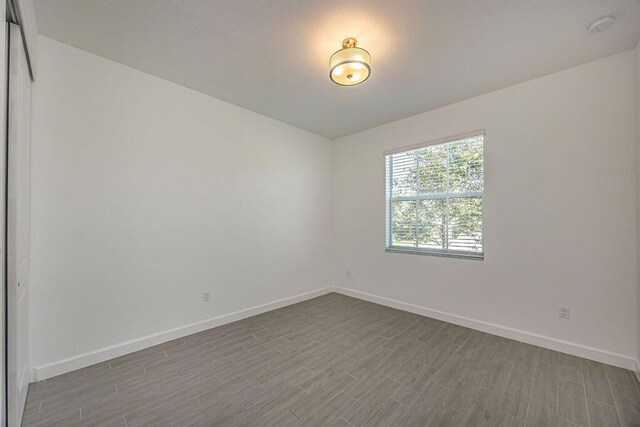 empty room with baseboards and dark wood-style floors