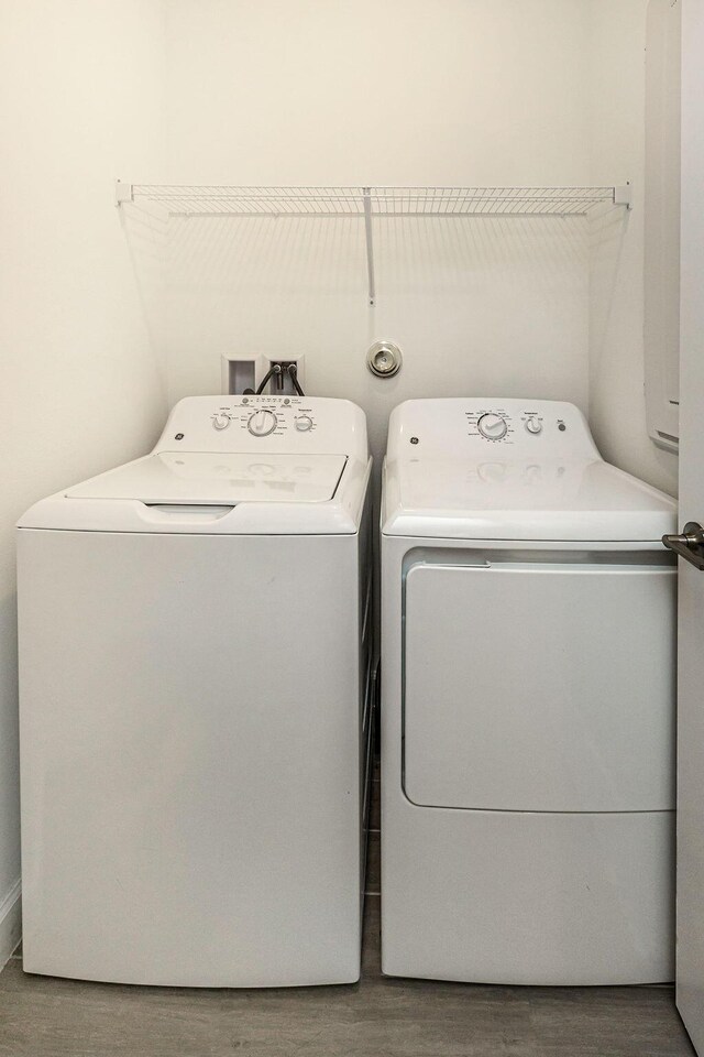 laundry area with laundry area, washing machine and dryer, and wood finished floors