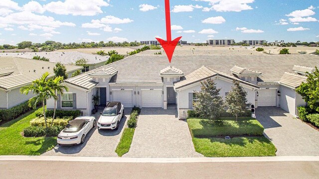 ranch-style house featuring a garage, stucco siding, driveway, and a tile roof