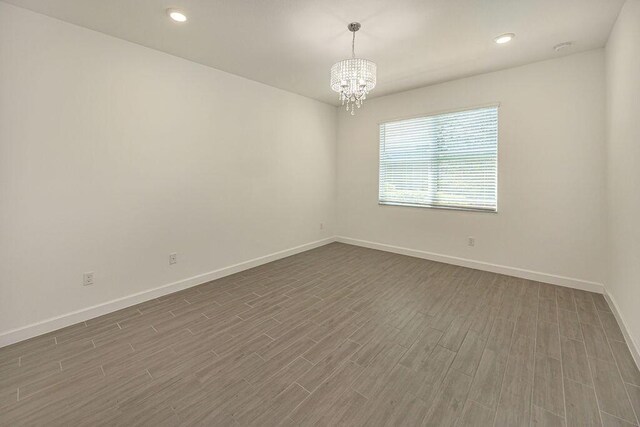 unfurnished room with recessed lighting, baseboards, a chandelier, and dark wood-type flooring
