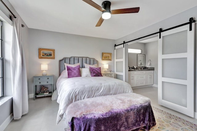 3399 Jog Park Dr, Greenacres, FL 33467 - bedroom featuring light tile patterned flooring, ceiling fan, a barn door, ensuite bath, and baseboards