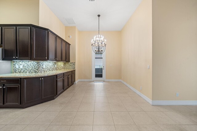 10765 Pisa Rd, Wellington, FL 33414 - kitchen with appliances with stainless steel finishes, dark brown cabinets, baseboards, light stone counters, and an inviting chandelier