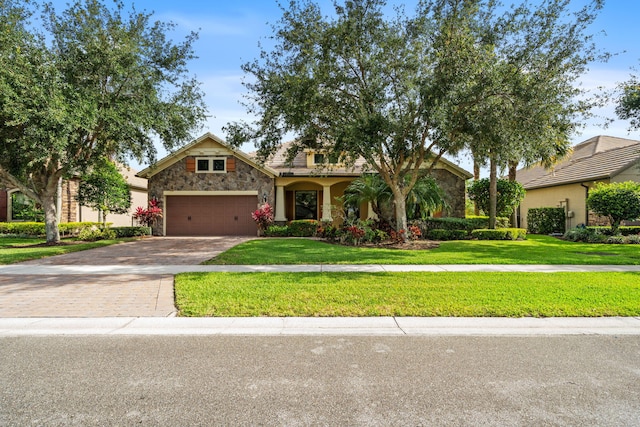10765 Pisa Rd, Wellington, FL 33414 - view of front of home with stone siding, a front lawn, an attached garage, and decorative driveway
