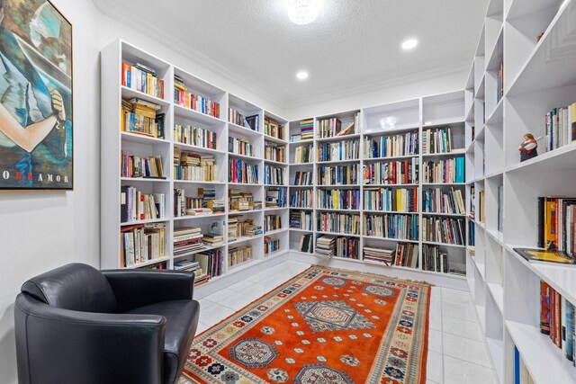 10056 Lexington Cir N, Boynton Beach, FL 33436 - sitting room with crown molding, a textured ceiling, wall of books, and tile patterned floors