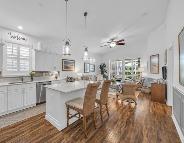 kitchen featuring dark wood-style flooring, dishwasher, a sink, light countertops, and open floor plan