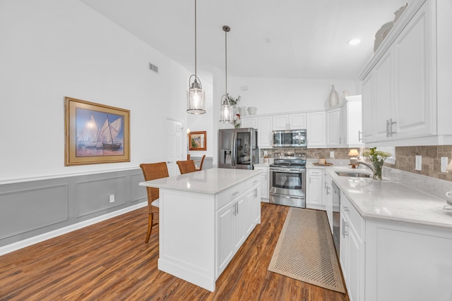 kitchen featuring decorative backsplash, dark wood-style flooring, a kitchen breakfast bar, white cabinets, and stainless steel appliances