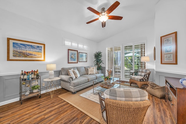 living room with a decorative wall, wood finished floors, a wainscoted wall, a ceiling fan, and vaulted ceiling