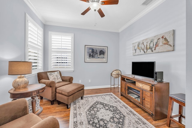 living room with ceiling fan, light wood-style flooring, baseboards, visible vents, and ornamental molding