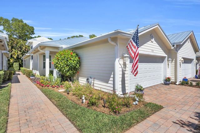 view of property exterior featuring an attached garage, decorative driveway, and metal roof