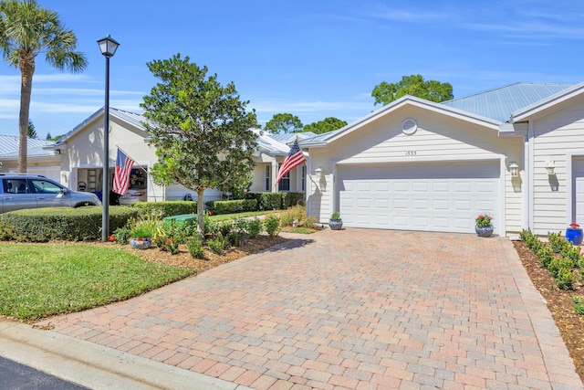 ranch-style home featuring a garage, a front lawn, and decorative driveway