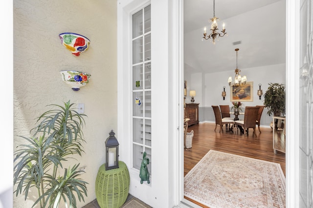 interior space with an inviting chandelier, wood finished floors, and visible vents