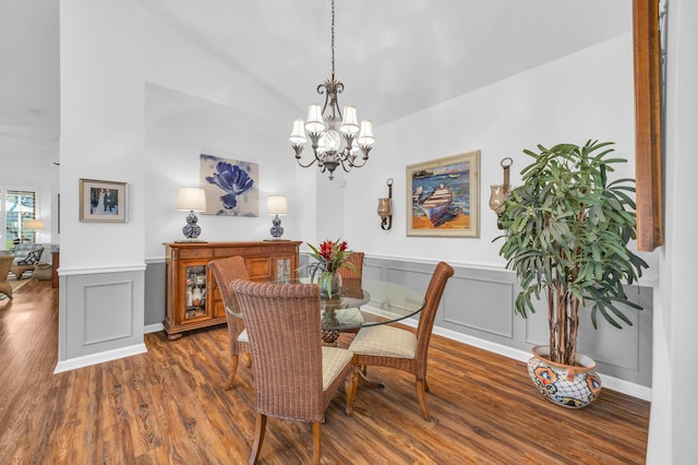 dining space with a decorative wall, wainscoting, wood finished floors, and a notable chandelier