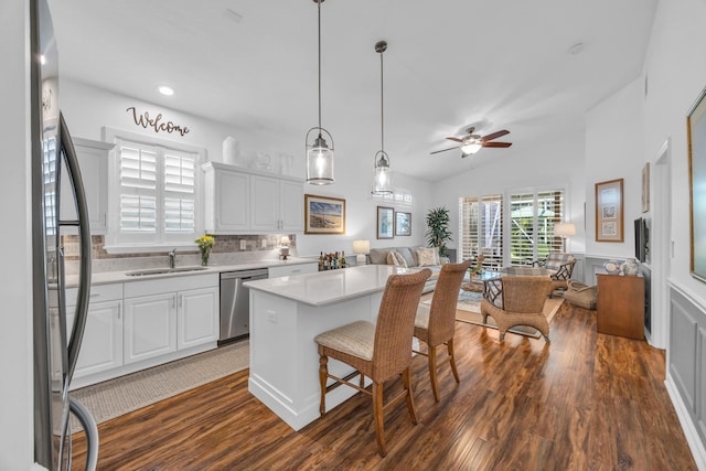 kitchen with appliances with stainless steel finishes, dark wood finished floors, a sink, light countertops, and open floor plan