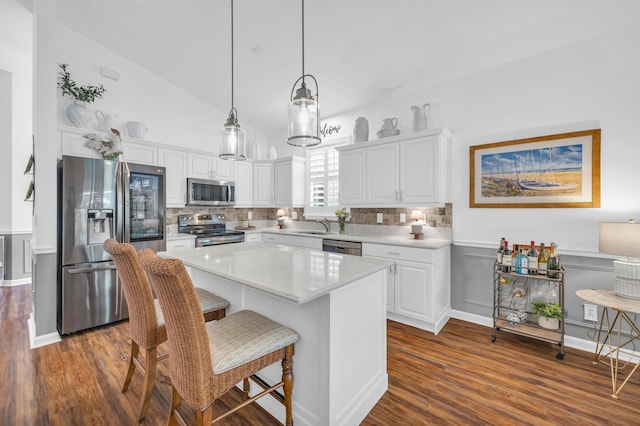 kitchen with dark wood-style floors, a center island, white cabinetry, a sink, and appliances with stainless steel finishes