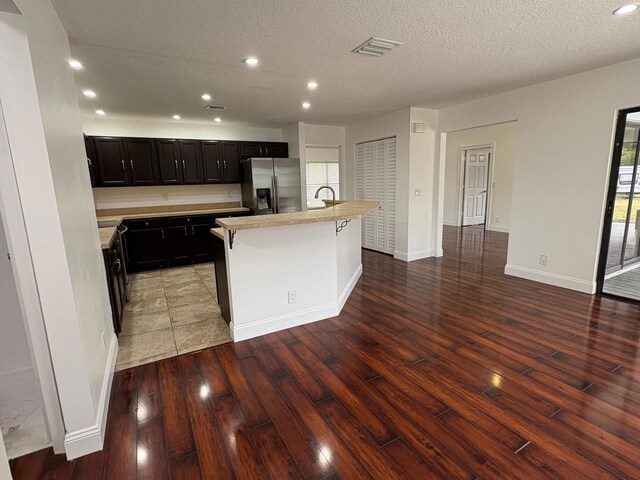 kitchen featuring stainless steel fridge, light countertops, recessed lighting, light wood-type flooring, and visible vents