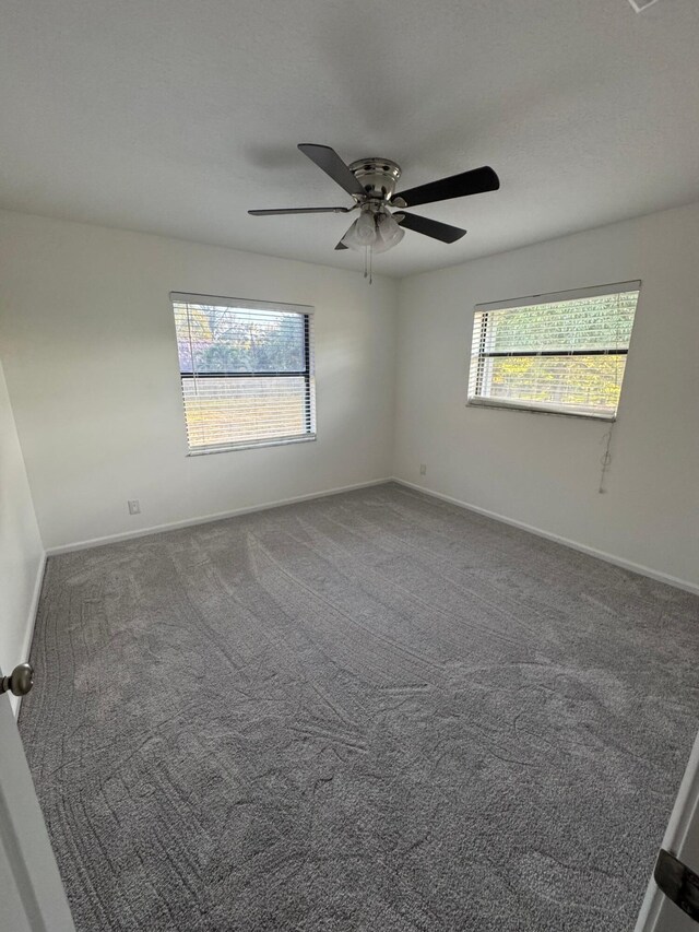 carpeted empty room featuring ceiling fan and baseboards