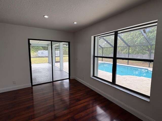 spare room with baseboards, recessed lighting, a textured ceiling, and dark wood finished floors
