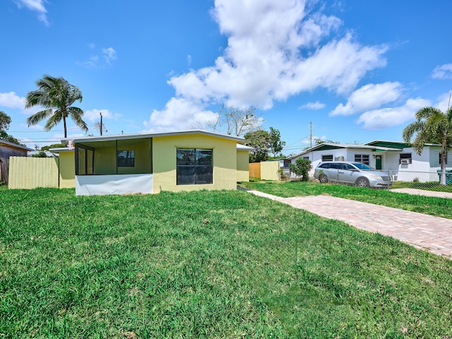 back of house featuring a lawn, fence, and brick siding