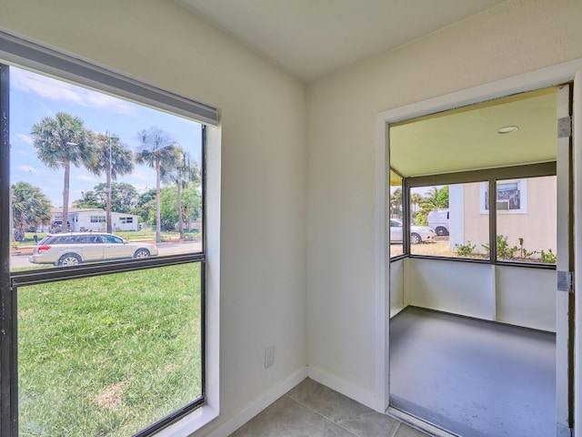 spare room featuring baseboards, tile patterned floors, and a healthy amount of sunlight