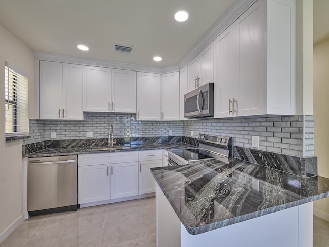 kitchen featuring visible vents, dark stone counters, white cabinetry, a sink, and stainless steel appliances
