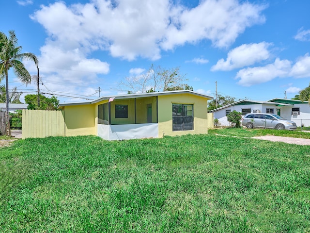 back of property with a lawn, stucco siding, and fence
