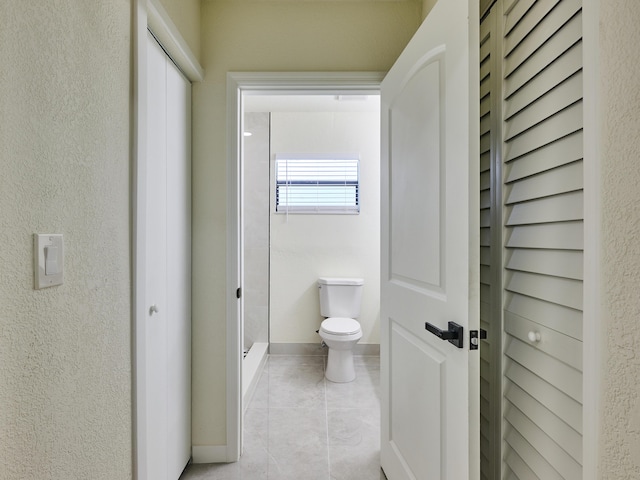 full bathroom with baseboards, tile patterned floors, toilet, and a shower stall