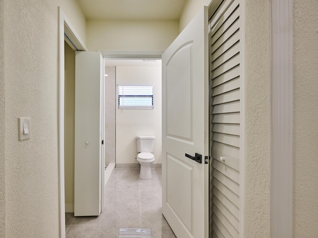 full bath featuring toilet, baseboards, tile patterned flooring, and a stall shower