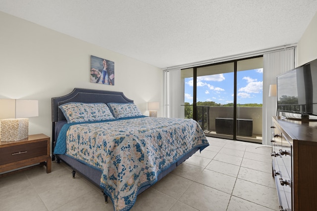 bedroom featuring light tile patterned floors, a textured ceiling, expansive windows, and access to exterior
