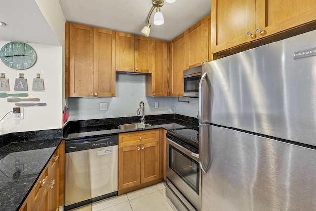 kitchen with a sink, light tile patterned floors, stainless steel appliances, and brown cabinets