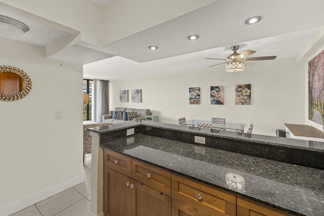 kitchen featuring open floor plan, recessed lighting, a ceiling fan, dark stone countertops, and light tile patterned floors