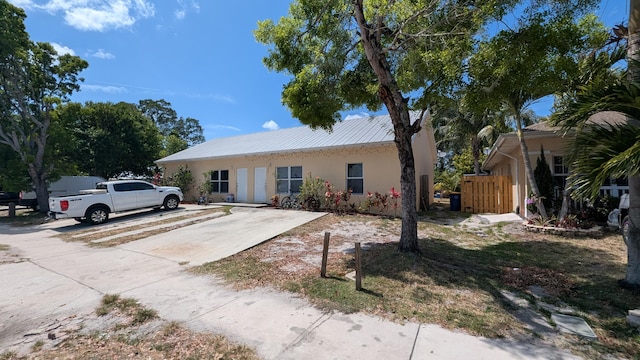 single story home with fence, stucco siding, and metal roof